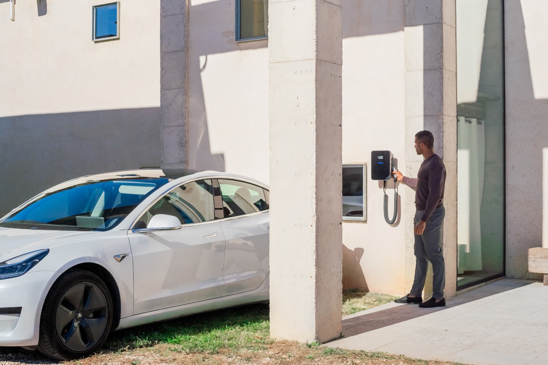 Vehículo eléctrico cargando con un V2C Trydan en una vivienda moderna